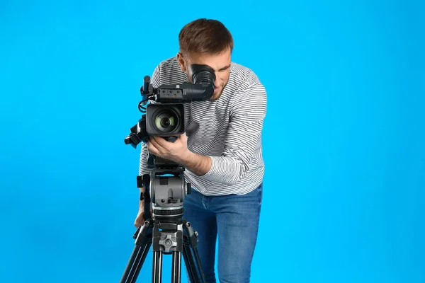 Operador com câmera de vídeo profissional em fundo azul — Fotografia de Stock