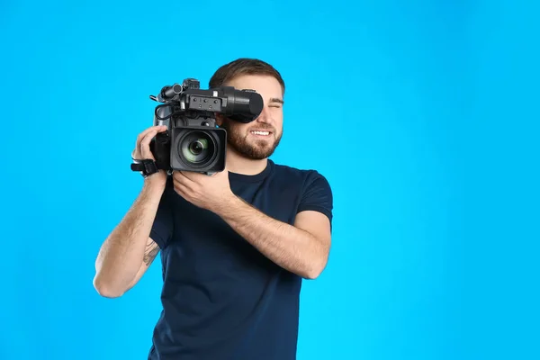 Operador com câmera de vídeo profissional em fundo azul — Fotografia de Stock