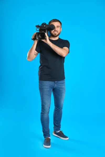 Opérateur avec caméra vidéo professionnelle sur fond bleu — Photo