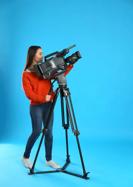 Bediener mit professioneller Videokamera auf blauem Hintergrund — Stockfoto