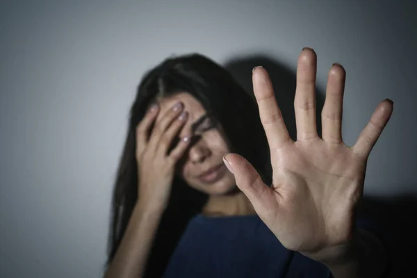 Piangendo giovane donna facendo gesto fermata vicino muro bianco, concentrarsi su — Foto Stock