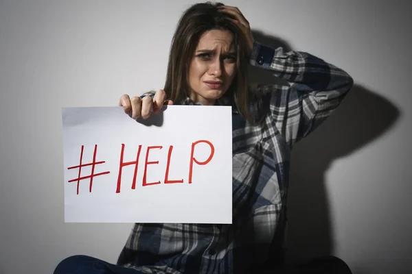 Eine weinende junge Frau mit Hashtag help in der Nähe der weißen Wand. Inland — Stockfoto