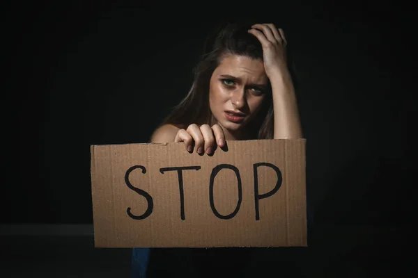 Plačící mladá žena s cedulí Stop na černém pozadí. Domácí — Stock fotografie