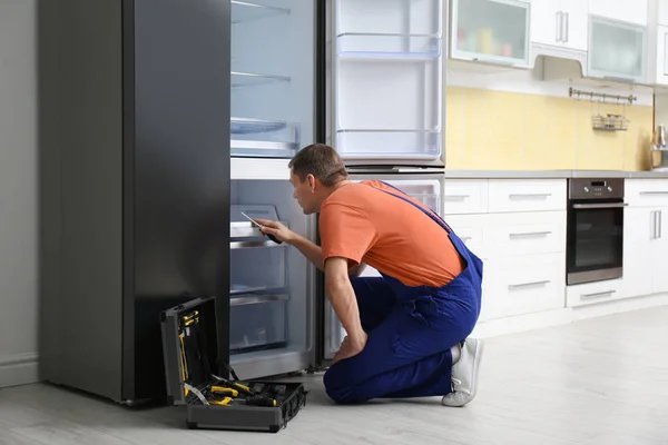 Techniker mit Schraubenzieher repariert Kühlschrank in Küche — Stockfoto