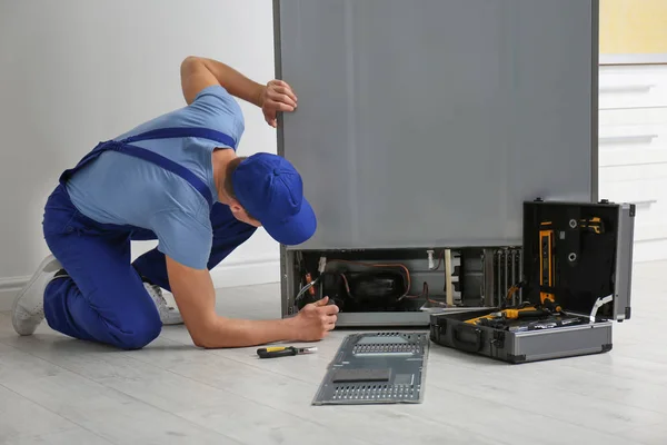 Manlig tekniker med skruvmejsel reparera kylskåp inomhus — Stockfoto