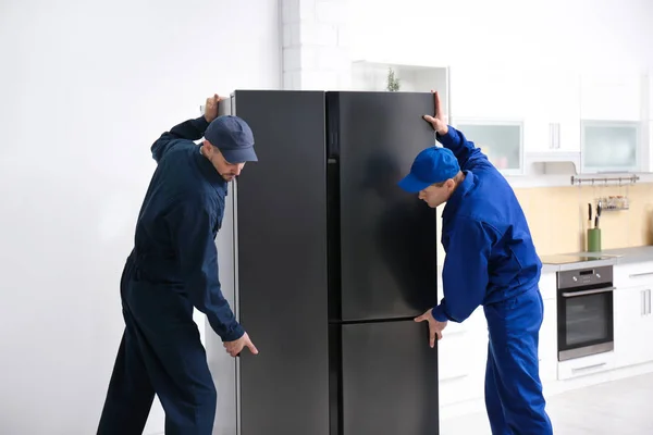 Profesionální Pracovníci Nesoucí Moderní Chladničku Kuchyni — Stock fotografie