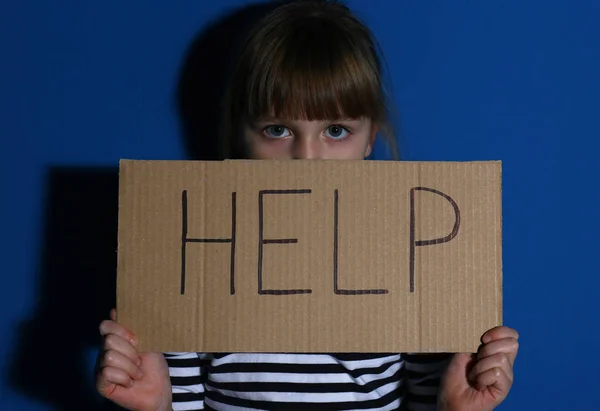 Menina abusada com sinal AJUDA perto da parede azul. Víola doméstica — Fotografia de Stock