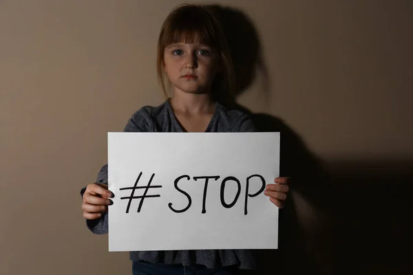 Κακοποιημένο κοριτσάκι με ετικέτα Stop κοντά σε μπεζ τοίχο. Εσωτερικό v — Φωτογραφία Αρχείου