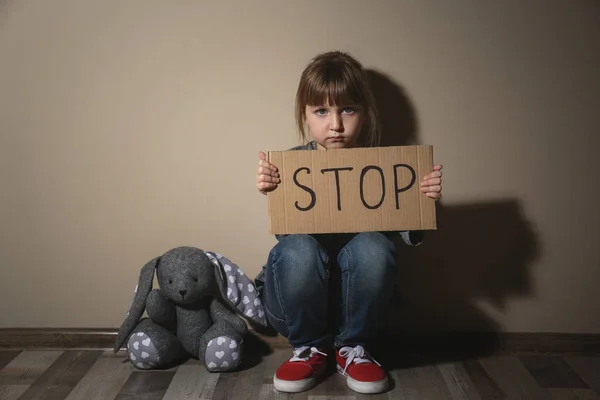 Зловживала маленька дівчинка зі знаком STOP біля бежевої стіни. Домашній скрип — стокове фото