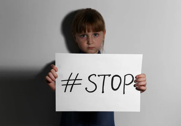 Niña maltratada con hashtag ALTO cerca de la pared blanca. Residentes v — Foto de Stock