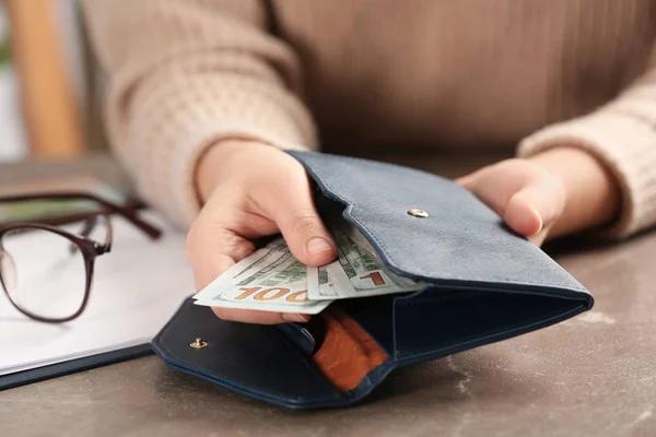 Mujer poniendo dinero en la cartera en la mesa marrón, primer plano —  Fotos de Stock