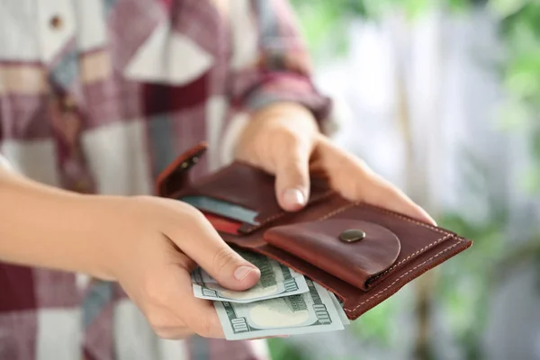 Woman putting money into wallet on blurred background, closeup — Stock Photo, Image