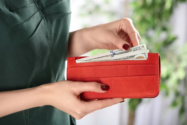 Женщина кладет деньги в бумажник на размытом фоне, крупным планом — стоковое фото