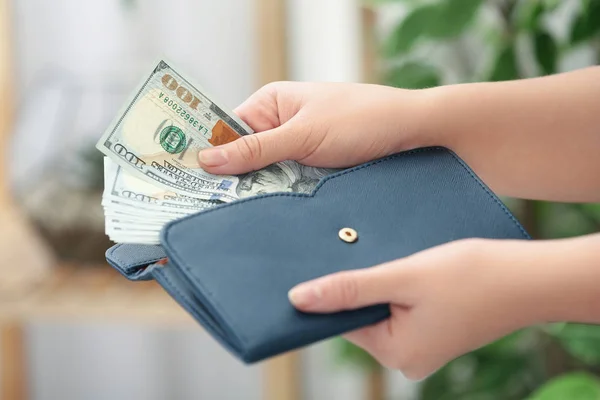 Γυναίκα βάζει χρήματα στο πορτοφόλι σε θολή φόντο, closeup — Φωτογραφία Αρχείου