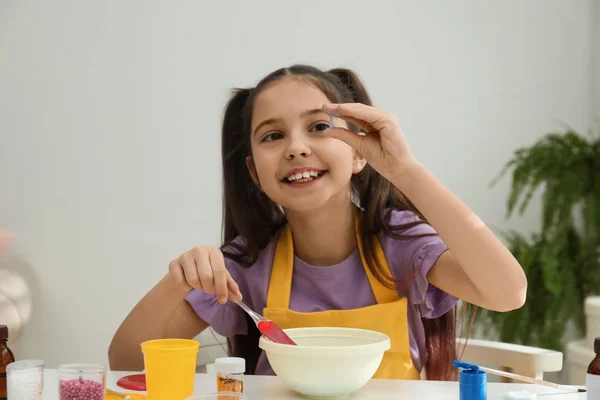 Linda niña haciendo limo juguete en la mesa en el interior — Foto de Stock