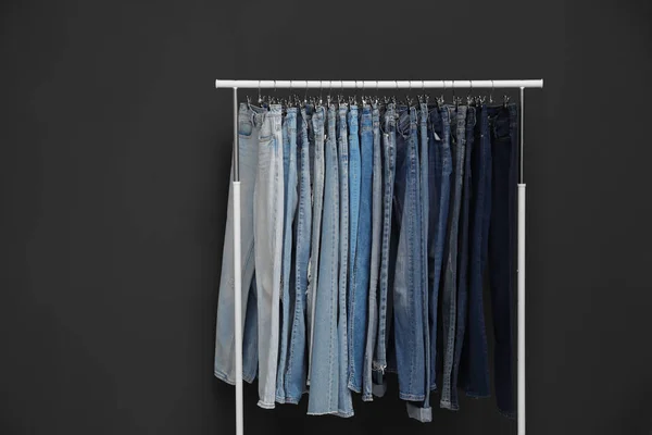 Scaffale con jeans diversi su fondo grigio scuro — Foto Stock