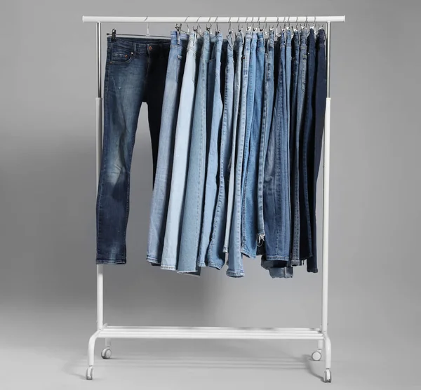 Cremalheira com jeans diferentes em fundo cinza — Fotografia de Stock