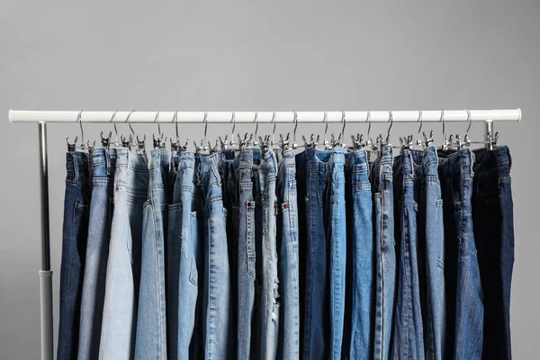 Bastidor con diferentes pantalones vaqueros sobre fondo gris —  Fotos de Stock