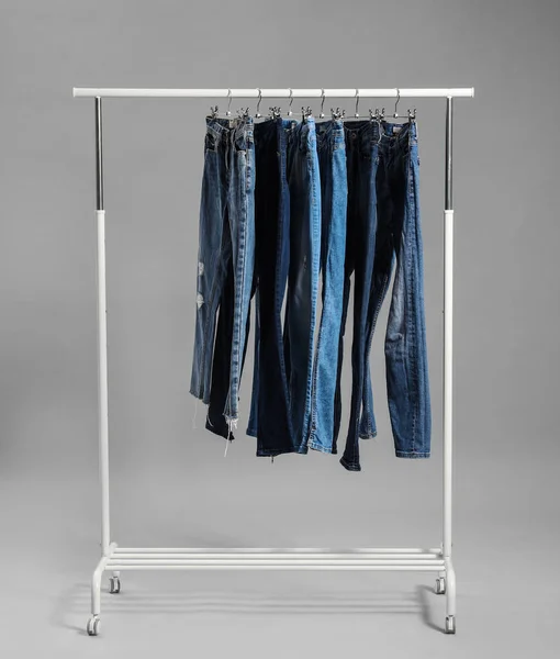 Gri arkaplanda farklı kot pantolon ile raf — Stok fotoğraf