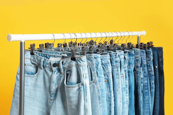 Cremalheira com jeans diferentes no fundo amarelo — Fotografia de Stock