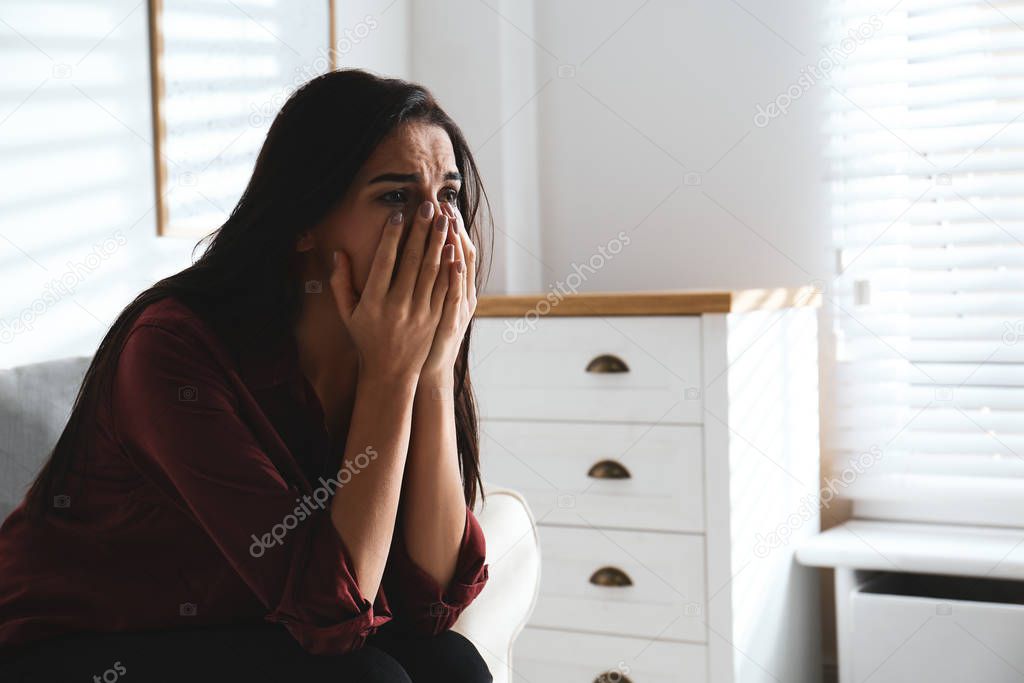 Abused young woman crying indoors, space for text. Domestic viol