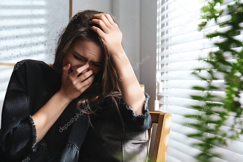 Abused young woman crying indoors. Domestic violence concept