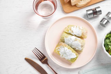 Lezzetli lahana ruloları beyaz ahşap masada servis edilir.