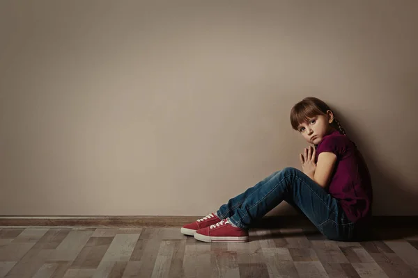 Грустная маленькая девочка сидит на полу в помещении, место для смс. Ребёнок — стоковое фото