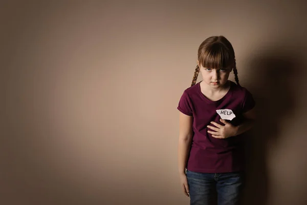 Печальная маленькая девочка с табличкой HELP на бежевом фоне, место для te — стоковое фото