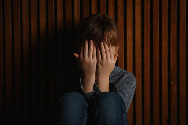 Little girl closing her eyes on wooden background. Child in dang
