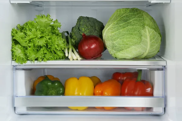 Open refrigerator full of fresh vegetables, closeup