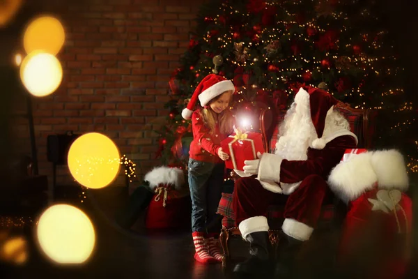 Санта-Клаус сделал подарок маленькой девочке возле елки в Нью-Йорке — стоковое фото