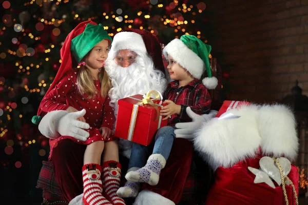 Santa Claus a malé děti s dárkem u vánočního stromečku — Stock fotografie