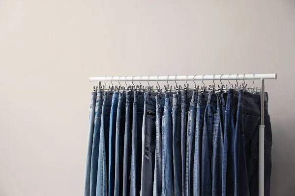 Rack with stylish jeans on beige background — ストック写真