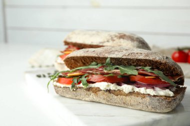 Taze sebzeli lezzetli sandviçler ve beyaz masada jambon.