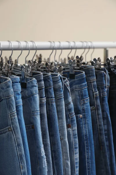 Rack with stylish jeans on color background, closeup — 스톡 사진