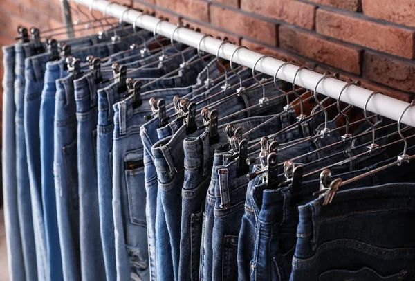 Cremalheira com jeans elegantes perto da parede de tijolo, close-up — Fotografia de Stock