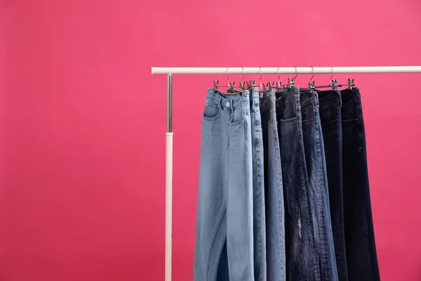 Cremalheira com jeans elegantes no fundo rosa — Fotografia de Stock