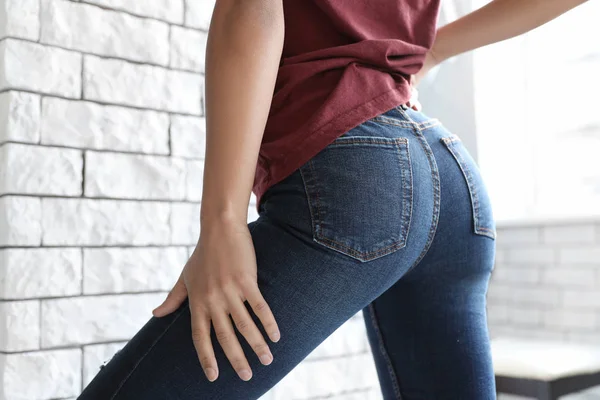 Mujer vistiendo jeans cerca de la pared de ladrillo en el interior, primer plano —  Fotos de Stock