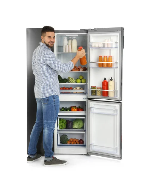 若い男取り冷蔵庫から白い背景にジュース — ストック写真