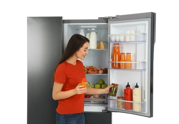Jovem mulher escolhendo produtos da geladeira no backgro branco — Fotografia de Stock