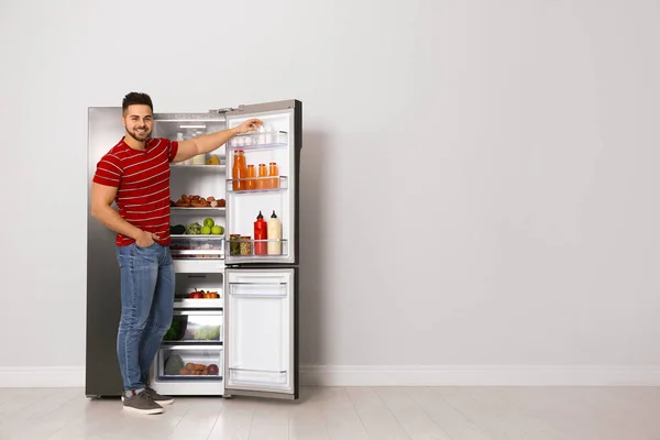 Молодой человек вынимает йогурт из холодильника в помещении, место для — стоковое фото