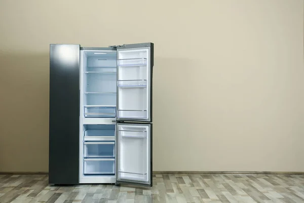 Modern refrigerator near beige wall, space for text — Stock Photo, Image