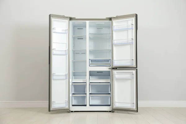 Современный пустой холодильник возле светло-серой стены. Бытовая техника — стоковое фото