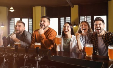Group of friends watching football in sport bar
