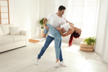 Güzel, genç bir çift oturma odasında dans ediyor.