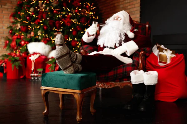 Санта Клаус Стаканом Молока Отдыхающий Кресле Возле Елки Сосредоточиться Ногах — стоковое фото