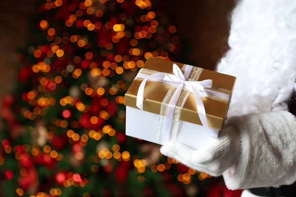 Papai Noel Segurando Presente Natal Contra Luzes Festivas Borradas Close — Fotografia de Stock