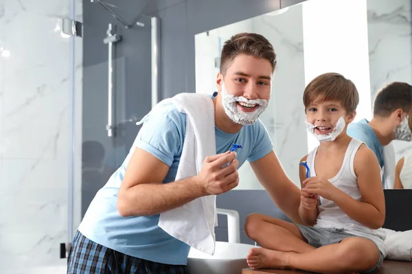 Pap en zoon met scheerschuim op hun gezicht in de badkamer — Stockfoto