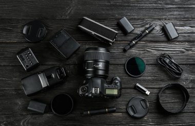 Siyah ahşap masada profesyonel fotoğrafçı için ekipmanla düz kompozisyon.